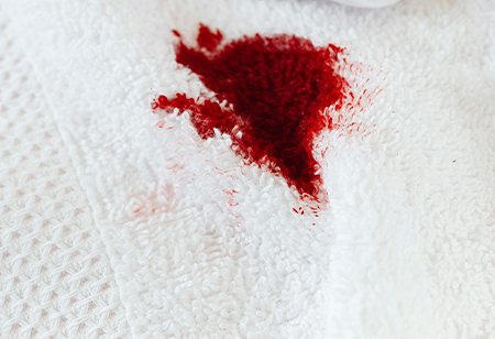 Prenda con una mancha de sangre enjuagada bajo agua fría